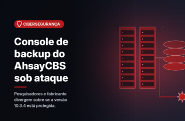 Ilustração gerada por computador (imagem ilustrativa, sem valor documental): em fundo escuro com brilho vermelho, dois racks de servidores e uma pilha de discos ligados por um fluxo de dados que se desvia para uma engrenagem. À esquerda, selo vermelho com símbolo de escudo e o texto 'Cibersegurança', o título 'Console de backup do AhsayCBS sob ataque' e a frase 'Pesquisadores e fabricante divergem sobre se a versão 10.3.4 está protegida.'